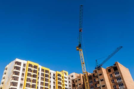 Crane and high rise building under construction against blue sky. Modern architecture background