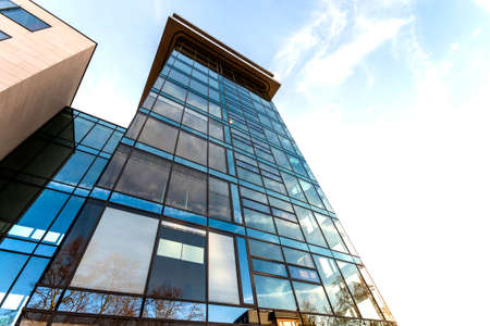 Low angle view of reflection of blue sky in glass wall of modern office building skyscraper in business districtの写真素材