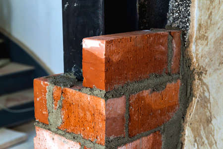 Close up of bricklaying industrial installing bricks on construction site wallの写真素材
