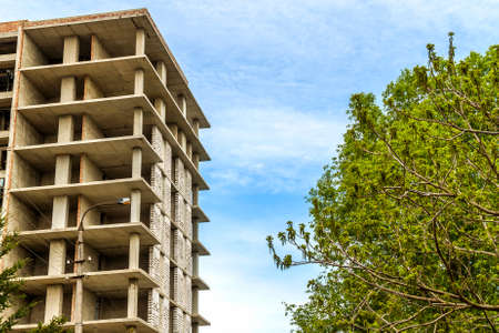 Modern building under construction against blue sky. Construction work site