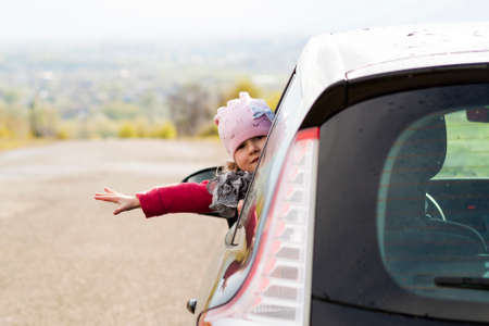 Pretty little girl in the car looking through car window. Travel concept.の写真素材