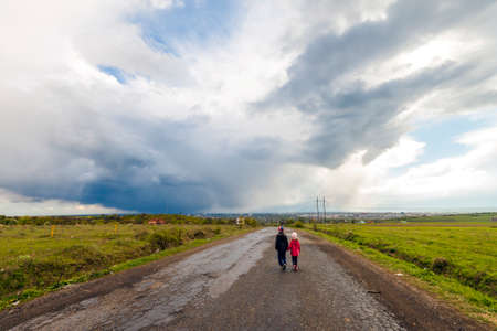 Two little children boy and girl walking on a roadの写真素材
