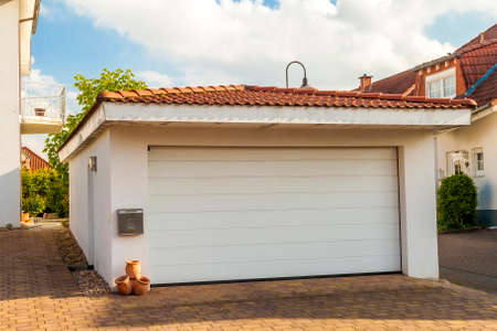 Detached white garage with orange brick tile roof