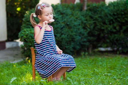 Little pretty girl in summer day eating an ice creamの写真素材