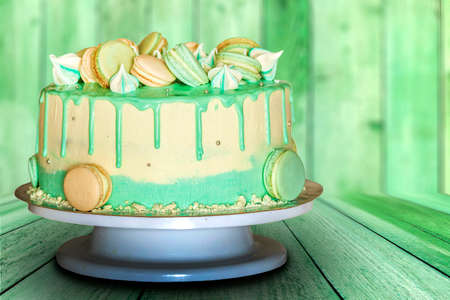 Green creamy cake with macaroons on green wooden backgroundの写真素材
