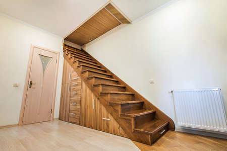 Modern architecture interior with  luxury hallway with glossy wooden stairs in modern storey house. Custom built pullout cabinets on glides in slots under stairsの写真素材