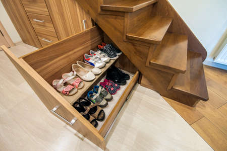 Modern architecture interior with  luxury hallway with glossy wooden stairs in modern storey house. Custom built pullout cabinets on glides in slots under stairsの写真素材