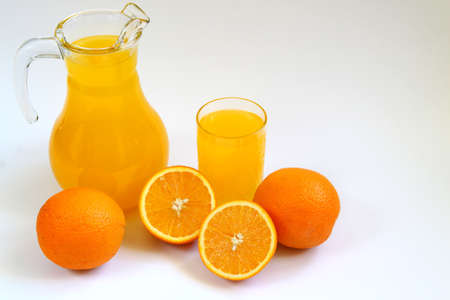 Jug and glass of orange juice and ripe oranges isolated on white background. Healthy nutrition conceptの写真素材