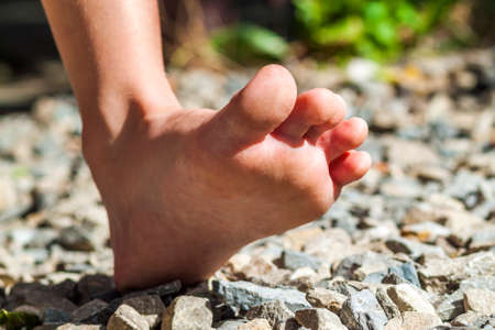 Close-up of bare foot walking on stones, outdoors activity