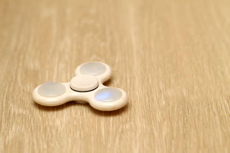 White fidget spinner toy on a wooden floorの写真素材