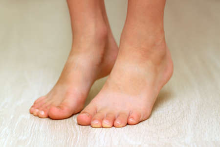 Child's feet on parquet laminate wooden texture floor close-up. Healthcare concept