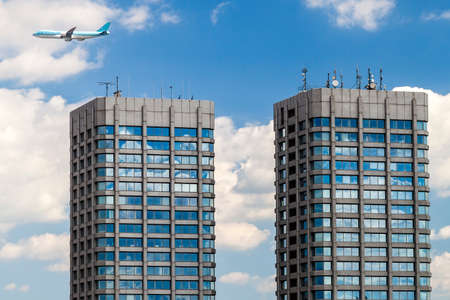Modern glass and concrete skyscrapers and a plane in the skyの写真素材