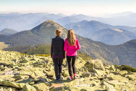 Two girls hikers standing in mountains enjoying mountain viewの写真素材