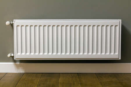 White heating radiator on wall in an apartment with wooden floorの写真素材