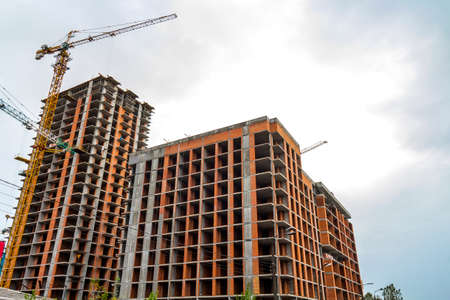 Tall modern concrete apartment building under construction with tower cranes.