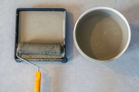 High angle of paint roller in tray with paint can on concrete floor.の写真素材