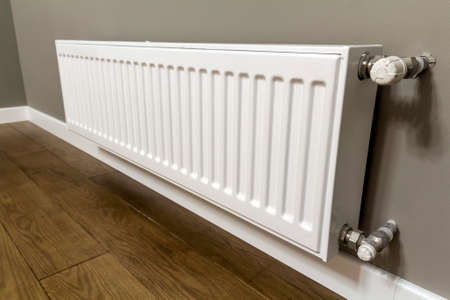 White heating radiator on wall in an apartment with wooden floorの写真素材