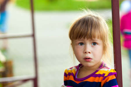 Little girl with funny expression on her face playing outdoors