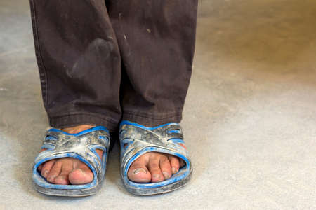 Feet of a person in old dirty clothes and shoesの写真素材