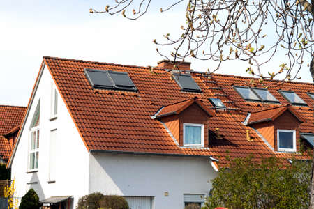 Roof of classic residential houses with orange roofing tiles and windows