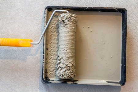 Paint roller in paint tray with grey color in the trayの写真素材