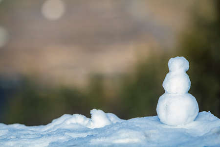 Little white snowman with blurred green background in winterの写真素材