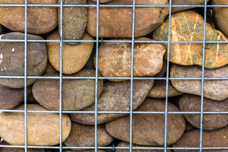 Abstract background of stones behind steel barsの写真素材