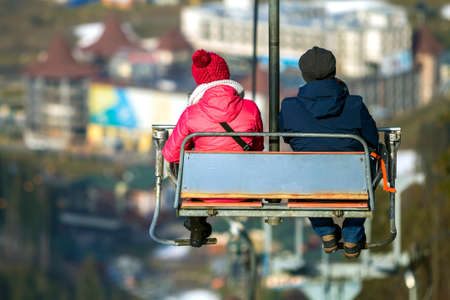 Yong pair riding chair lift on vacation in mountainsの写真素材