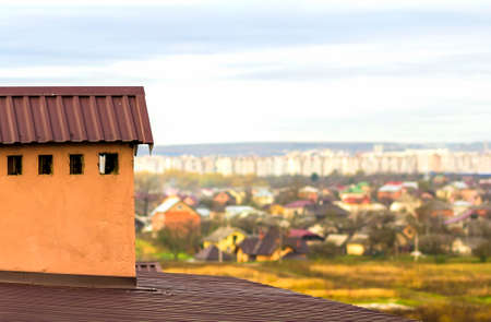 Chimney on a roof of a new built house with view of a city belowの写真素材
