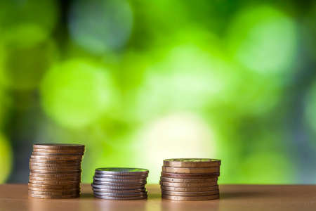 Ñoins stacks with green and blue sparkling bokeh background. Financial growth, saving money,...