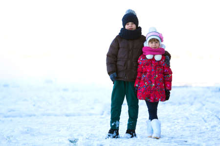 Portrait of two children boy and girl playing outdoors in winter snowy dayの写真素材