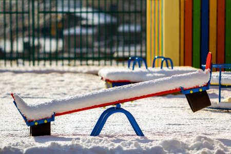 Playground in kindergarten for children in winter with snow covered swingsの写真素材