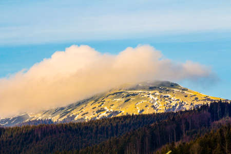Mountain with white puffy cloud on it