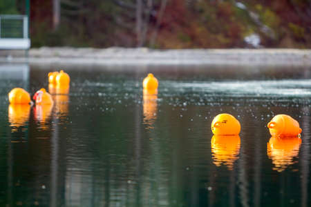 Yellow buoys against the blue water. Restriction on open water. Glare and ripples on the water.