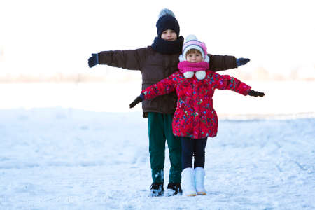 Portrait of two children boy and girl playing outdoors in winter snowy dayの写真素材