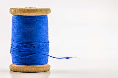 Reel or spool of blue sewing thread isolated on white. Shallow depth of field. Close-up macro shot.