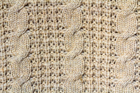 Background texture of beige pattern knitted fabric made of cotton or wool closeup
