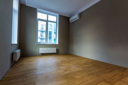 New renovated room interior with big windows, air conditioner, heating radiators and wooden parquet...