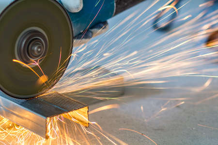 Close-up of worker cutting metal with grinder. Sparks while grinding iron.