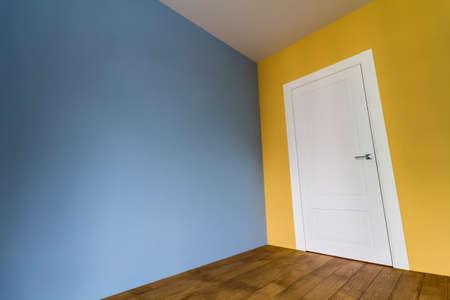 Fresh painted room interior with white door and wooden parquet floor after renovationの写真素材