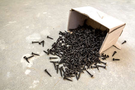 Close-up image of many small black screws on concrete backgroundの写真素材