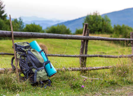 Hikers camping backpack leaning on old wooden fence. Tourist equipment