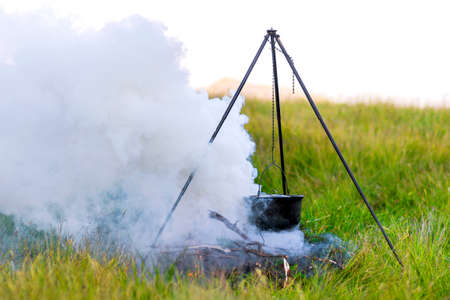 Camping kitchenware - pot on the fire at an outdoor campsite with thick white smokeの写真素材