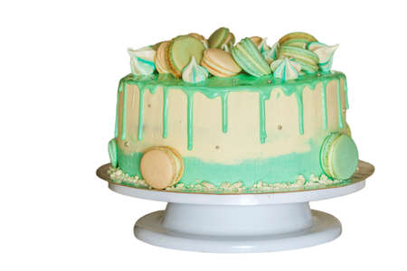Sweet creamy green cake with macaroons on top isolated on white
