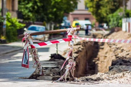 Construction roadwork on street in city. Red safety sign warns about roadworks. Be careful, danger...