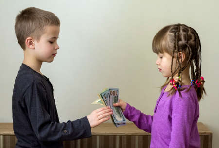 Two little children boy and girl playing with dollars moneyの写真素材