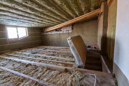 House attic under construction. Mansard walls and ceiling insulation with rock wool. Fiberglass insulation material in wooden frame for cold barrier.の写真素材