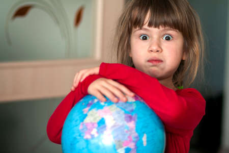 Portrait of the cute little girl hugging the earth globe. Education and save the earth concept. Pretty child looking in the camera.の写真素材