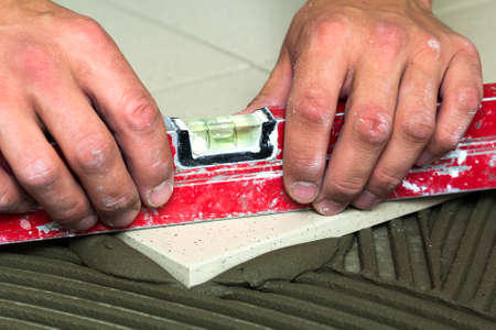 Ceramic tiles and tools for tiler. Worker hand installing floor tiles. Home improvement, renovation...