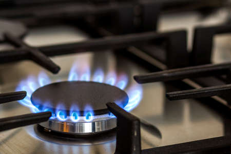 Natural gas burning on kitchen gas stove in the dark. Panel from steel with a gas ring burner on a black background, close-up shooting.の写真素材